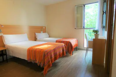 a hotel room with two beds and a window at Hotel de Montaña La Rocha in Quesa