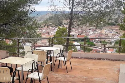 a patio with tables and chairs and a view of a city at Hotel de Montaña La Rocha in Quesa