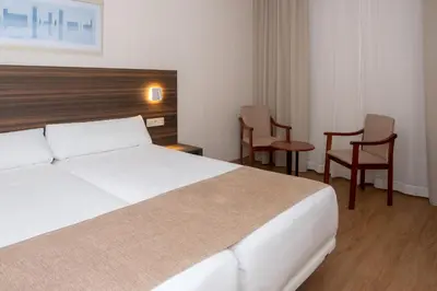 a hotel room with a bed and two chairs at Hotel Belcaire in Vall de Uixó