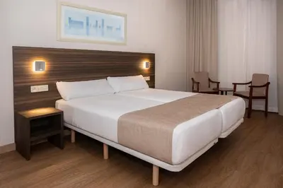 a bedroom with a large bed and two chairs at Hotel Belcaire in Vall de Uixó