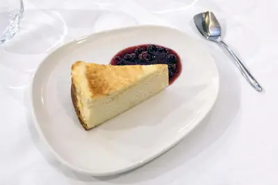 a piece of cake on a white plate with blueberry sauce at Hotel Belcaire in Vall de Uixó