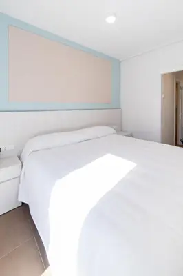 a bedroom with a white bed and a blue wall at Hotel Alkazar in Valencia