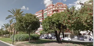 a tall pink building with trees in front of a street at KOA Centric, comfy in Ruzafa in Valencia