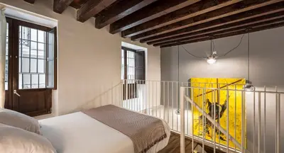 a bedroom with a bed and a yellow suitcase at Catalina Suites San Nicolas in Valencia