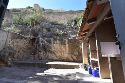 a stone wall with a stairway next to a building at La Muralla Del Castillo in Chulilla