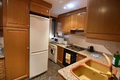 a kitchen with wooden cabinets and a white refrigerator at La Muralla Del Castillo in Chulilla