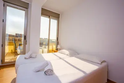 two beds in a white room with a large window at Cap Blanc Penthouse in Cullera