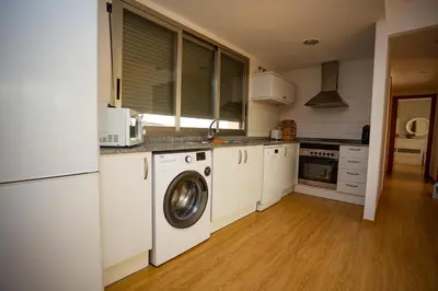 a kitchen with white cabinets and a washer and dryer at Cap Blanc Penthouse in Cullera