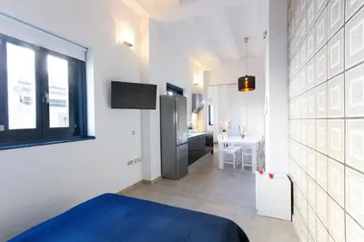 a white room with a blue bed and a kitchen at Valentia Apartments - Mercado Central in Valencia