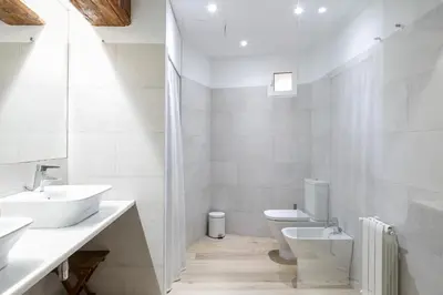 a white bathroom with two sinks and a toilet at ApartUP L' Almoina in Valencia