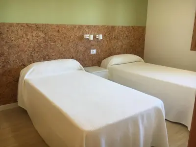 two beds in a room with white sheets at Apartamentos Satse Moncofa in Moncófar