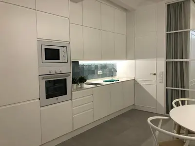 a white kitchen with white cabinets and a table at Apartamento Frederick “Centrico y con Clase” in Valencia