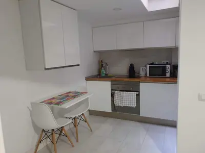 a kitchen with white cabinets and a table and chairs at Loft Office in Valencia