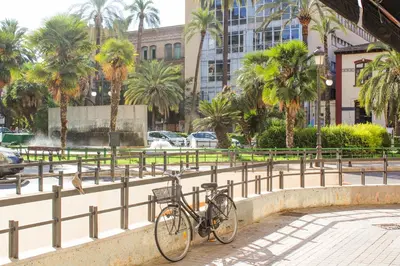 a bike parked next to a fence with palm trees at Valencia Apartamentos Goya in Valencia