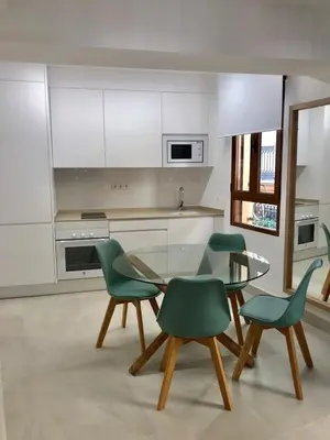 a kitchen with a glass table and green chairs at Apartamento Joseph , luminoso, bonito y muy céntrico in Valencia