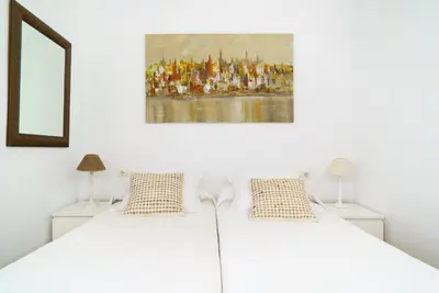 a bedroom with a white bed with a painting on the wall at Vivaldi Valencia in Valencia