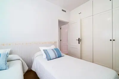 two beds in a bedroom with white cabinets and blue pillows at Vivaldi Valencia in Valencia