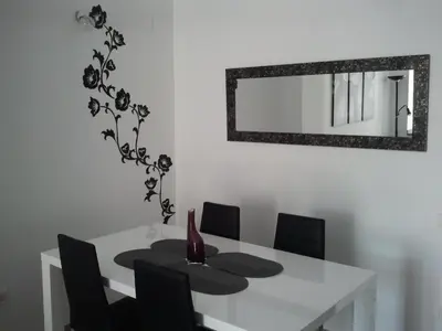 a white dining room table with black chairs and a mirror at Carrer de Dénia in Valencia