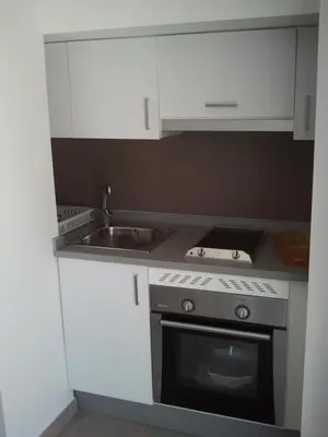 a kitchen with white cabinets and a stove and a sink at Carrer de Dénia in Valencia