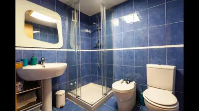 a blue tiled bathroom with a toilet and a sink at Apartamento en la Ciudad de las Ciencias y cerca de la playa in Valencia