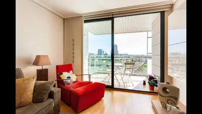 a living room with a red chair and a large window at Apartamento en la Ciudad de las Ciencias y cerca de la playa in Valencia