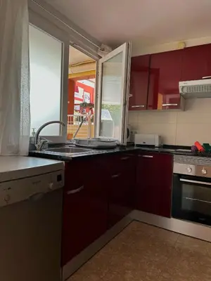 a kitchen with red cabinets and a sink and a window at Apartamento Barbacoa, Piscina y playa in Puebla de Farnals