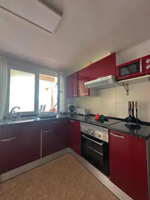 a kitchen with red cabinets and a sink and a stove at Apartamento Barbacoa, Piscina y playa in Puebla de Farnals