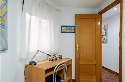 a desk with a lamp and a chair next to a window at My House in Valencia