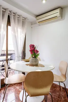 a white table with chairs and a vase of flowers at My House in Valencia