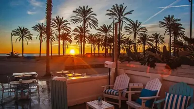 a view of a beach with palm trees and a sunset at Cool Loft Malvarrosa Beach in Valencia