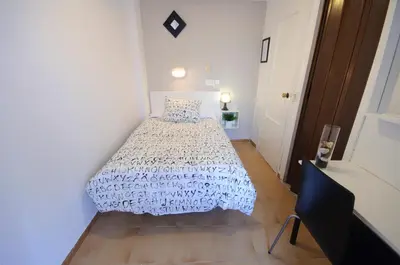 a bedroom with a bed with a white comforter at Hostal On Dormire Valencia in Valencia