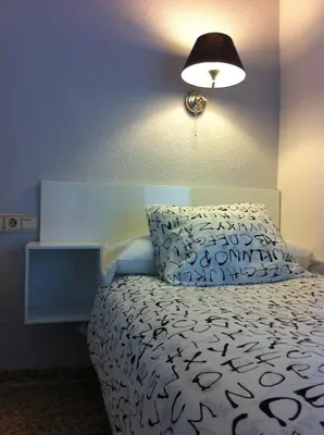 a bedroom with a bed with a pillow and a lamp at Hostal On Dormire Valencia in Valencia