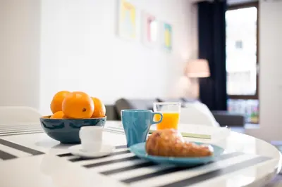 a table with a bowl of oranges and a glass of orange juice at Cabanyal Home in Valencia