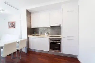 a kitchen with white cabinets and a table and chairs at Ático Valencia Centro in Valencia