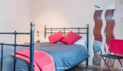 a bedroom with a bed with red pillows and a chair at AA la Nueva Fe in Valencia