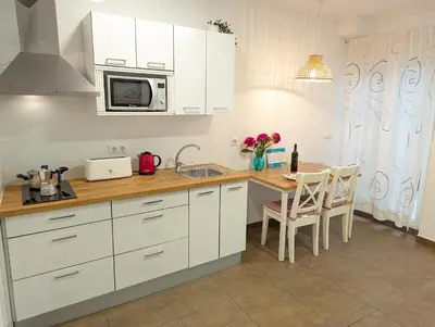 a kitchen with white cabinets and a table with chairs at Estudios en la playa in Valencia