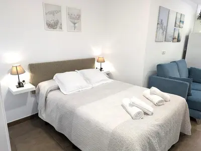 a bedroom with a bed and a blue chair at Estudios en la playa in Valencia