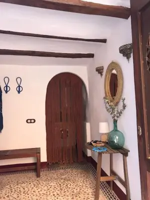a hallway with a wooden door and a table with a vase at Casa Rural La Antigua in Chelva