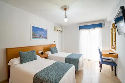 a hotel room with two beds and a desk at Hostal RR Feria by Beleret in Valencia