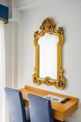 a gold mirror on a wall next to a desk at Hostal RR Feria by Beleret in Valencia