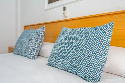 a bed with blue and white pillows on it at Hostal RR Feria by Beleret in Valencia