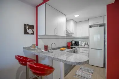 a kitchen with a counter and two red stools at Apartment on the beach,pool,WiFi,garage,Valencia in Valencia