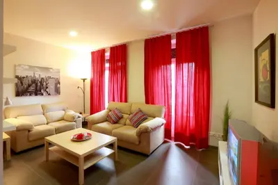 a living room with red curtains and a couch and a table at Reino de Valencia Apartments in Valencia