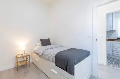 a white bedroom with a bed and a small table at Travel Habitat Ruzafa Apartment in Valencia