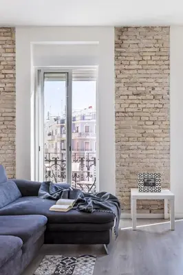 a living room with a couch and a brick wall at Travel Habitat Ruzafa Apartment in Valencia