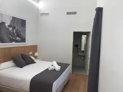 a bedroom with a white bed and a bathroom at Old Town Flats Casa Burguerini in Valencia