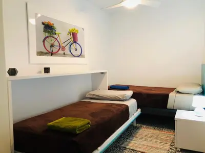 a room with two beds and a bike painting on the wall at Apartamento cerca de la playa y Ciudad de las Ciencias in Valencia