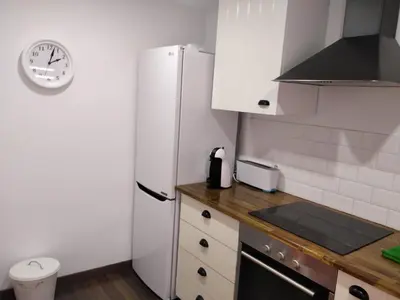 a kitchen with a refrigerator and a clock on the wall at Apartamento cerca de la playa y Ciudad de las Ciencias in Valencia