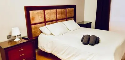 a bedroom with a white bed with a wooden headboard at APARTAMENTO CERCA DE PLAYA Y MONTAÑA IDEAL FAMILIAS O RELAX in Puzol