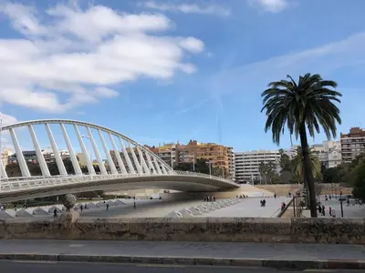 a bridge over a plaza with a palm tree and buildings at Colón Market Downtown in Valencia